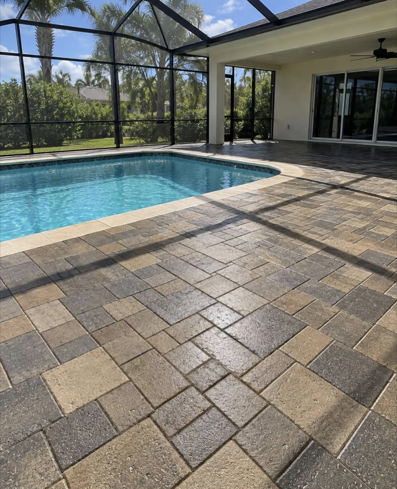 Finished paver pool deck beside a screened swimming pool